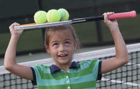 kid balancing tennis balls on racket on top of her head